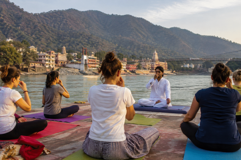 Pranayama class in Rishikesh with a traditional yoga teacher guiding students by the Ganga River
